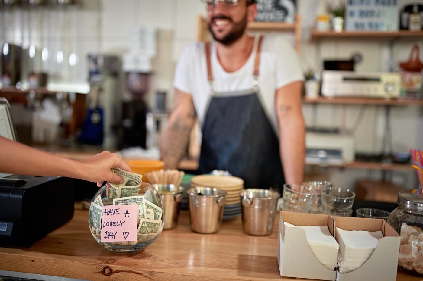 Merchant accepting payment at a coffee shop counter